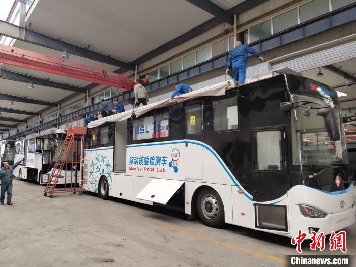 工人在組裝5G智能移動核酸檢測車車頂設(shè)備。 王鵬 攝